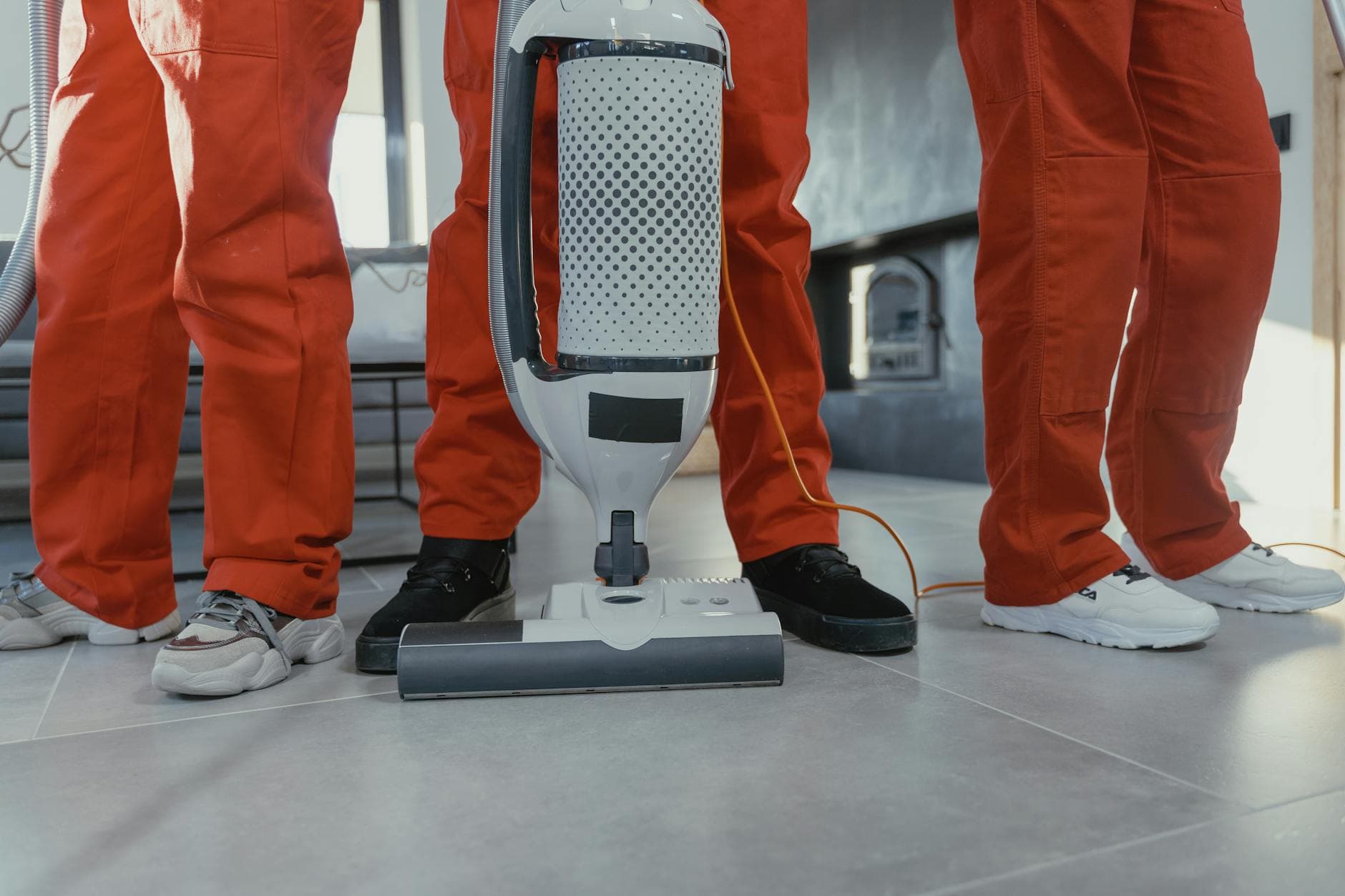 A team of professional Your Business cleaners in red uniforms using a vacuum in a New York home — Same-Day Cleaning in NYC