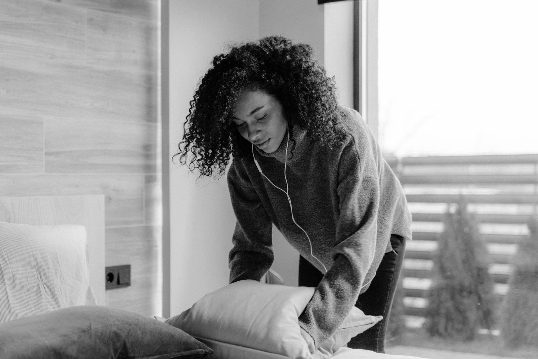 NYC maid service making the bed in a bright, monochrome bedroom — cleaning services in Bronxville, Westchester